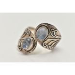 A SILVER MOONSTONE DRESS RING, of a cross over design, set with two oval moonstone cabochons, each