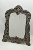 AN EDWARDIAN SILVER MOUNTED WILLIAM COMYNS & SONS EASEL BACK DRESSING TABLE MIRROR, the repoussé