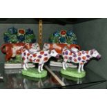 FOUR PIECES OF COW THEMED POTTERY, comprising two cow creamers with red and pink lustre patches,