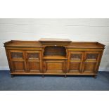 A LONG EARLY 20TH CENTURY OAK BOOKCASE, the double fielded and carved panel doors, below a