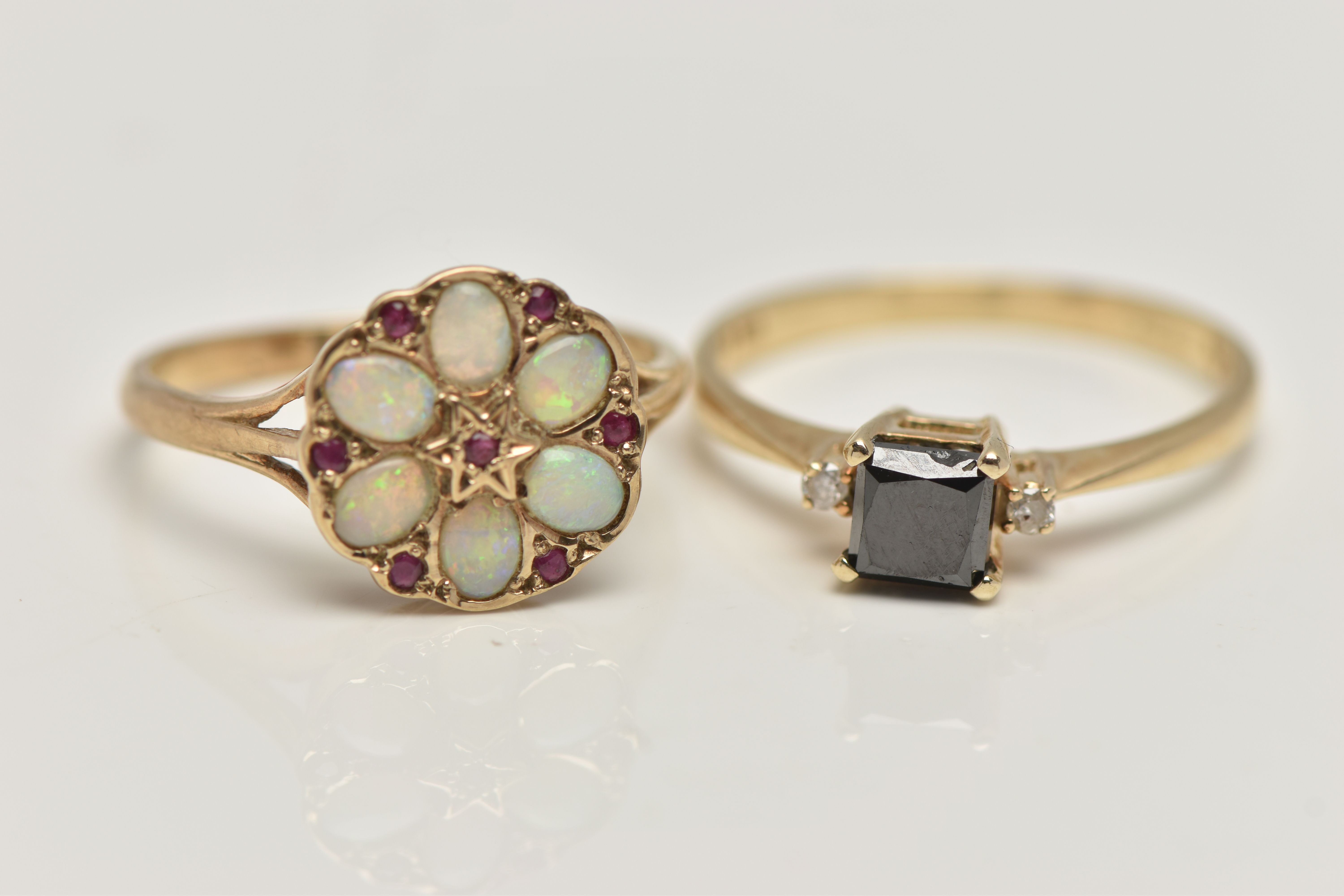 TWO GEM SET RINGS, the first a yellow gold ring set with a princess cut black diamond, flanked