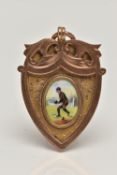 AN EARLY 20TH CETURY 9CT GOLD MEDAL, shield form with a central oval painting of a man playing