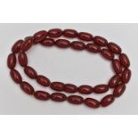 A STRING OF BAKELITE BEADS, small oval cherry amber beads, swirls visible, fitted with a screw