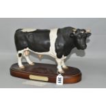 A ROYAL DOULTON FRIESIAN BULL, standing on a wooden plinth, model no A2580, height including