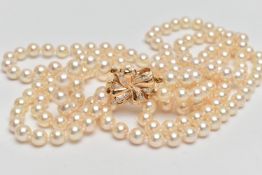 A CULTURED PEARL NECKLACE, designed with three strands of individually knotted cream pearls with a