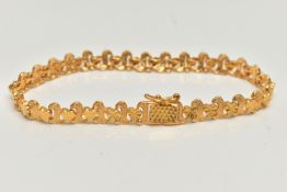 A YELLOW METAL ARTICULATED BRACELET, designed as a row of hearts interspaced with scrolls, fitted