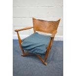 A MID CENTURY ARMCHAIR, with a leather strap back, shaped arm rests (condition:- leather torn and