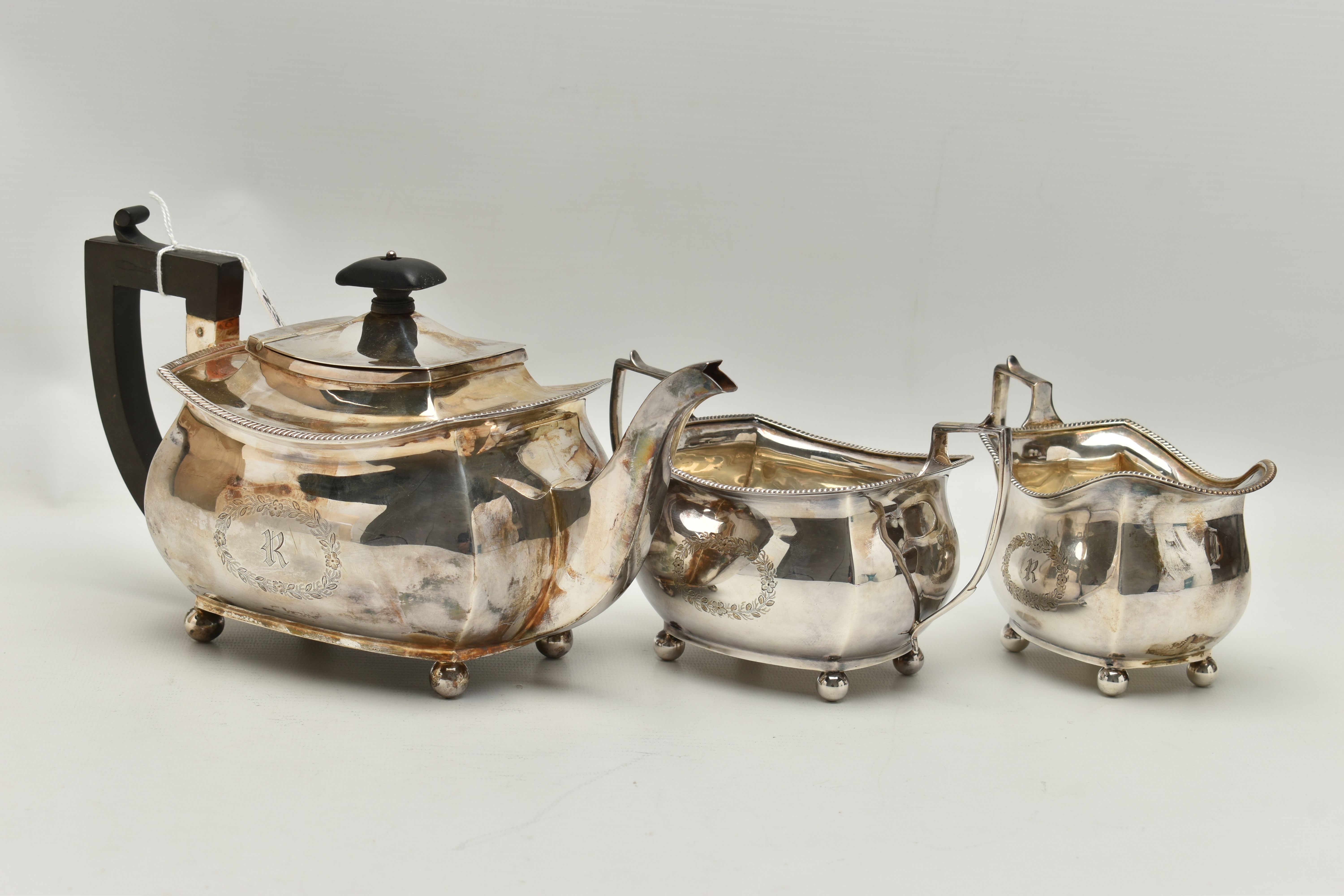 A GEORGE V THREE PIECE SILVER TEA SET, comprising of a polished teapot with engraved initial 'R'
