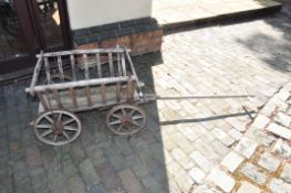 A SMALL VINTAGE WOODEN CART with iron banded wheels and replacement pine bed width 59cm length of