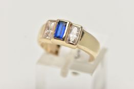 A YELLOW METAL CUBIC ZIRCONIA RING, set with one blue and two colourless cubic zirconia stones, wide