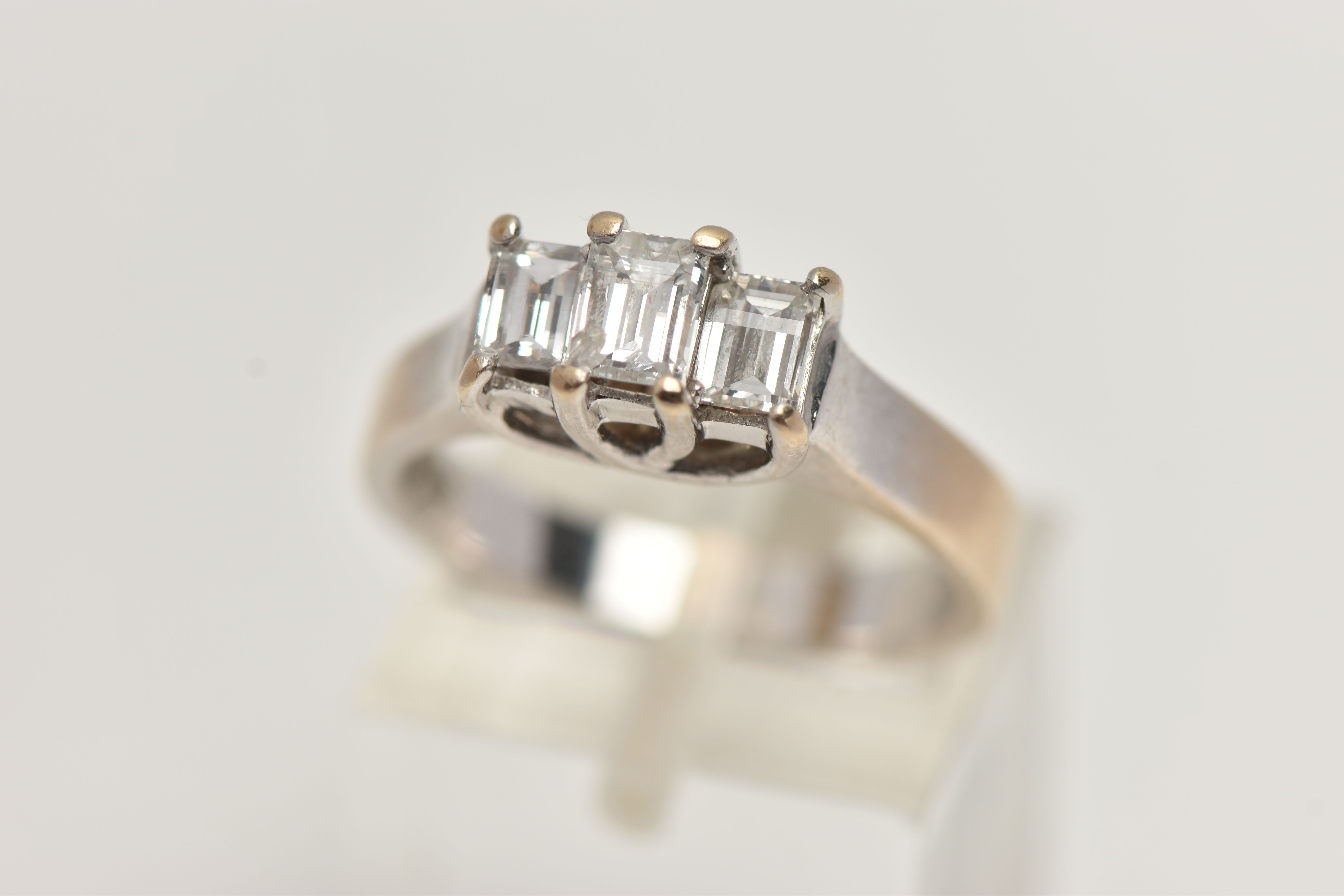 AN 18CT GOLD THREE STONE DIAMOND RING, the tiered design claw set with three millennium cut