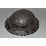 A BRITISH MILITARY STYLE STEEL HELMET, complete with liner and canvas chin strap, distressed black