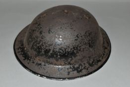 A BRITISH MILITARY STYLE STEEL HELMET, complete with liner and canvas chin strap, distressed black