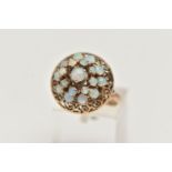 A YELLOW METAL OPAL RING, tiered ring set with opal cabochons, to the openwork scroll surround,