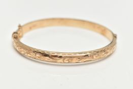 A 9CT GOLD HINGED BANGLE, engraved floral pattern to the front, fitted with an integrated push piece