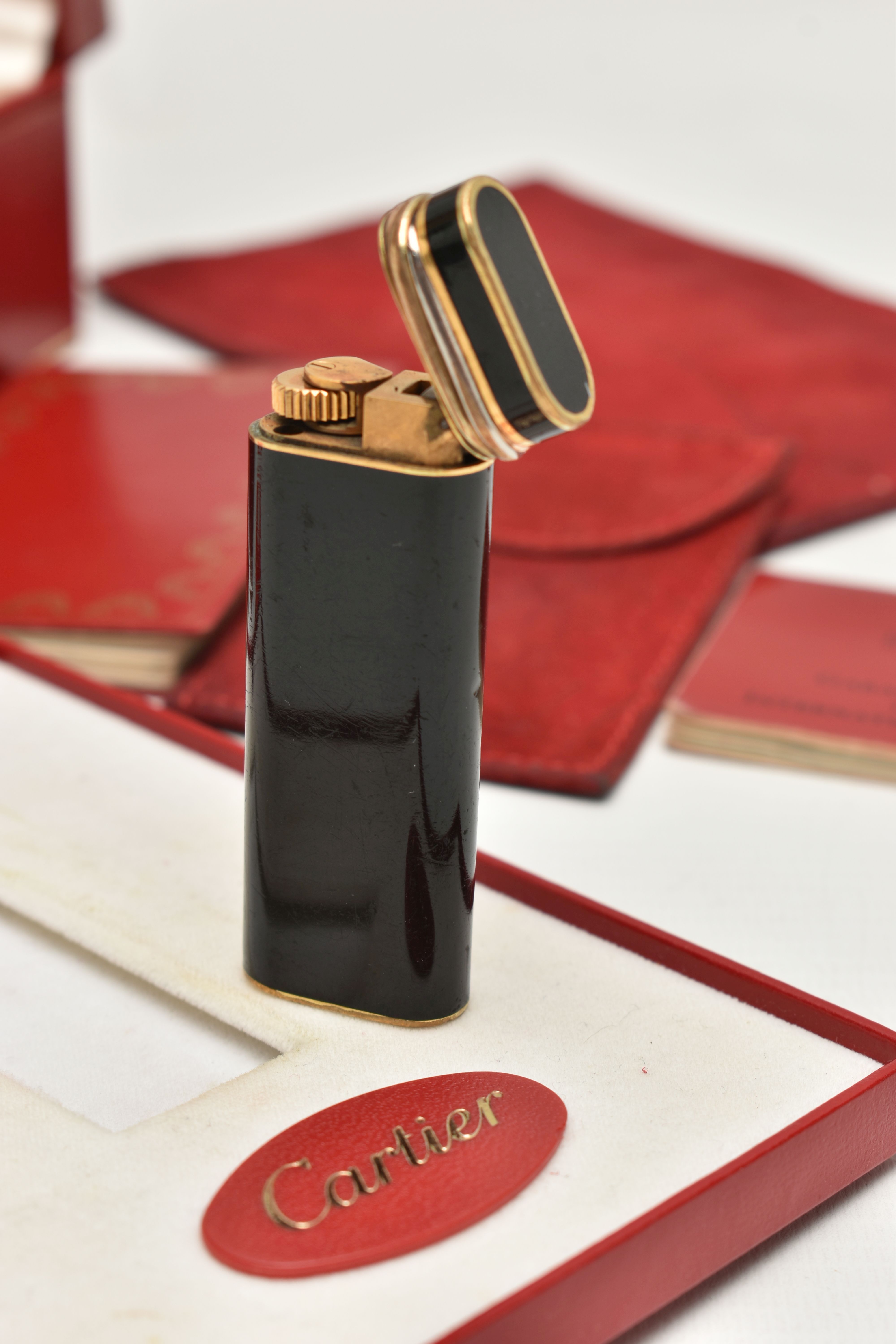 A 'MUST DE CARTIER' LIGHTER, gilt lighter with black lacquer and trinity band, serial 28008T, with a - Image 3 of 5