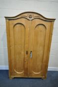 A VICTORIAN PINE TWO DOOR CUPBOARD, with an arched top, the panelled doors enclosing three