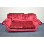 A RED VELVETEEN UPHOLSTERED TWO SEATER SETTEE, on turned legs and brass casters, length 202cm x