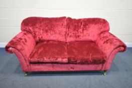 A RED VELVETEEN UPHOLSTERED TWO SEATER SETTEE, on turned legs and brass casters, length 202cm x