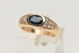 A YELLOW METAL SAPPHIRE AND DIAMOND RING, designed with a central oval cut deep blue sapphire,