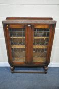 A 20TH CENTURY OAK LEAD GLAZED TWO DOOR BOOKCASE, with raised back, floral decoration, on turned