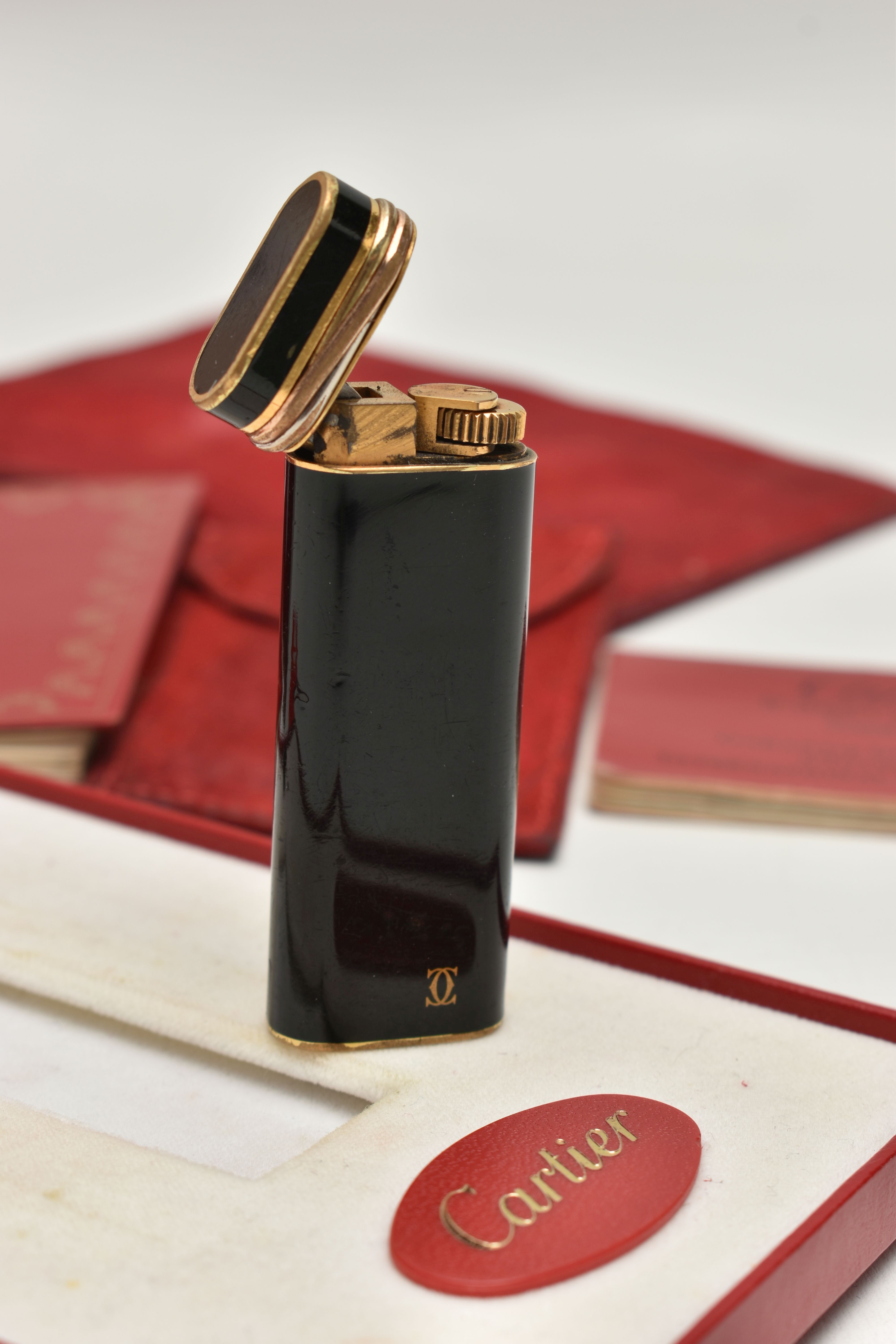 A 'MUST DE CARTIER' LIGHTER, gilt lighter with black lacquer and trinity band, serial 28008T, with a - Image 2 of 5