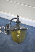 AN EARLY TO MID 20TH CENTURY WROUGHT IRON WALL MOUNTED LANTERN, with a tapered yellow glass shade (