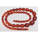 A STRING OF GRADUATED BAKELITE BEADS, graduating light red oval beads, largest measuring 25.4mm x