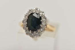 AN YELLOW METAL SAPPHIRE AND DIAMOND CLUSTER RING, set with an oval cut deep blue sapphire, claw set