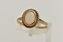 A 9CT GOLD OPAL CABOCHON RING, oval cut opal cabochon, collet set with a fine rope twist surround,
