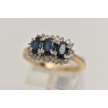 A 9CT GOLD SAPPHIRE AND DIAMOND CLUSTER RING, desinged with three oval cut deep blue sapphires, each