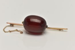 A CHERRY BAKELITE BEAD BROOCH, a large single, oval bead measuring approximately length 28.1mm x