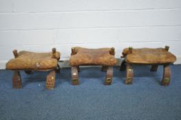 THREE CAMEL STOOLS, of various patterns each with leather cushions (condition report: - all with