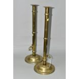 A PAIR OF VICTORIAN STYLE TALL BRASS CANDLESTICKS WITH LOCKABLE PUSHERS TO THE SIDES, one lacking