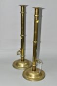 A PAIR OF VICTORIAN STYLE TALL BRASS CANDLESTICKS WITH LOCKABLE PUSHERS TO THE SIDES, one lacking