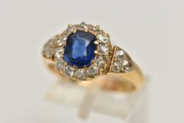 A YELLOW METAL SAPPHIRE AND DIAMOND CLUSTER RING, centring on a cushion cut blue sapphire, measuring