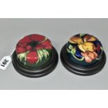 TWO MOORCROFT POTTERY PAPERWEIGHTS, set in wooden plinths, tube lined in Anemone and Miss Alice