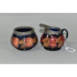 A MOORCROFT POTTERY POMEGRANATE PATTERN CREAM JUG AND SUGAR BOWL, tube lined with fruit on a dark