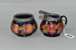 A MOORCROFT POTTERY POMEGRANATE PATTERN CREAM JUG AND SUGAR BOWL, tube lined with fruit on a dark