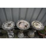 THREE WEATHERED COMPOSITE BIRD BATHS, of various styles, one in the form of a tree, one with