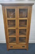A SOLID GOLDEN OAK GLAZED TWO DOOR BOOKCASE, with three shelves, over a single drawer, width 98cm