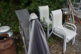 A SET OF FOUR FOLDING GARDEN CHAIRS, along with a parasol and a set of four cream stacking garden