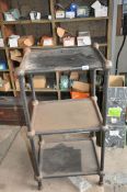 AN EARLY 20th CENTURY CAST IRON AND SHEET STEEL THREE TIER WORKSHOP TABLE with black painted finish,