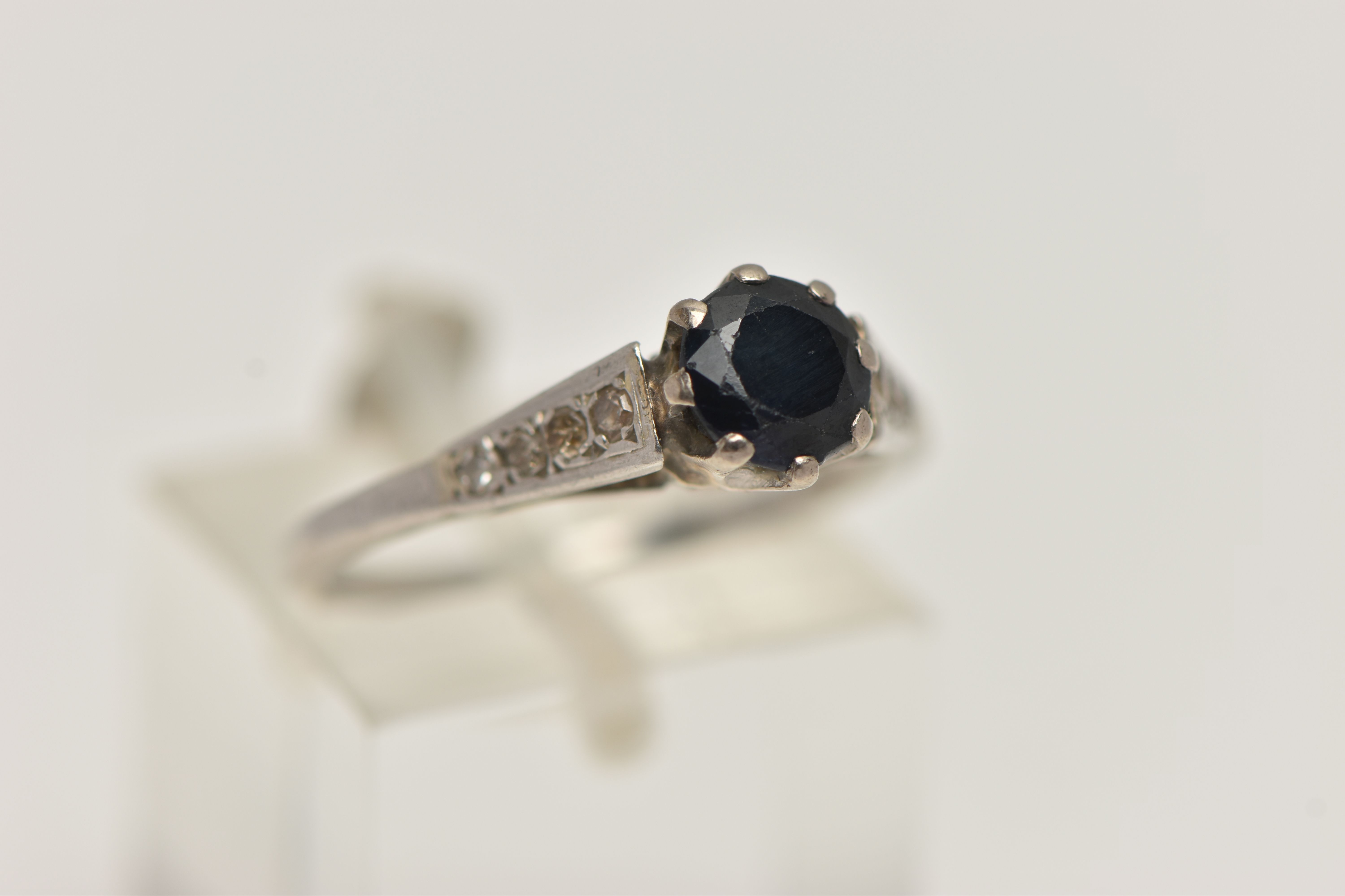 A WHITE METAL GEM SET RING, a circular cut sapphire in a prong setting, leading on to tapered - Image 4 of 4
