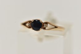 A YELLOW METAL SAPPHIRE AND DIAMOND RING, centring on a circular cut deep blue sapphire, four claw