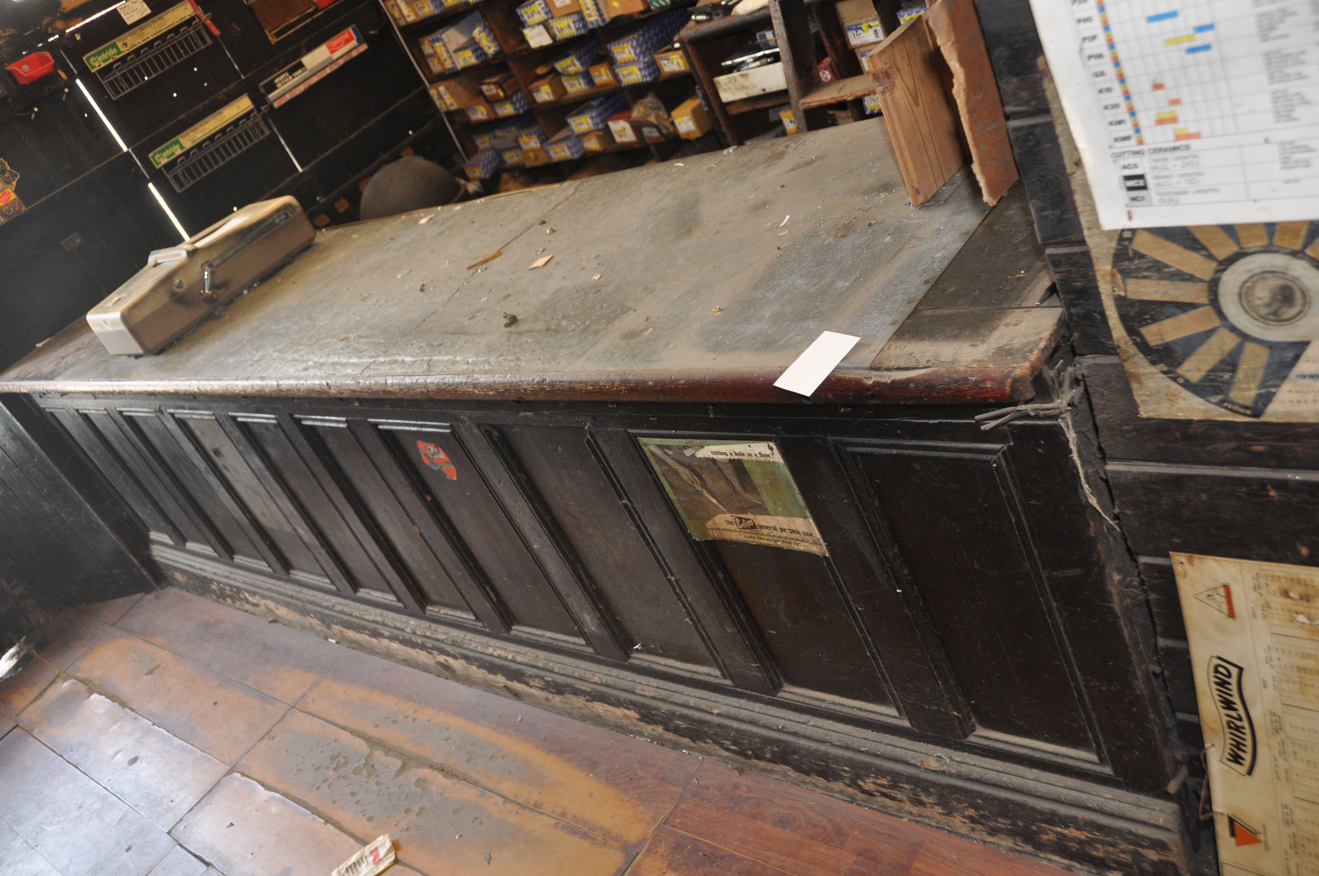 AN EARLY 20th CENTURY SHOP COUNTER with panelled front, pine plant top, zink plate and Rabone and