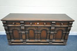 A REPRODUCTION CARVED OAK SIDEBOARD, with three drawers over four doors, width 180cm x depth 58cm