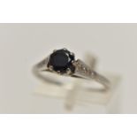 A WHITE METAL GEM SET RING, a circular cut sapphire in a prong setting, leading on to tapered
