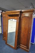 A VICTORIAN FLAME MAHOGANY TRIPLE DOOR COMPACTUM WARDROBE, the outer doors flanking a central mirror