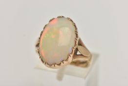 A 9CT GOLD OPAL RING, large oval opal cabochon, showing flashes of all the colours in the